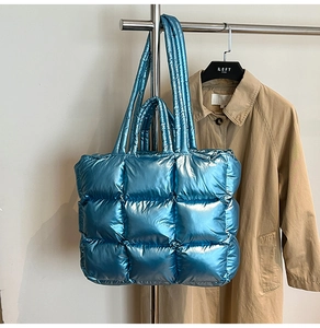 Close-up of metallic blue quilted puffer tote bag with glossy finish and matching shoulder strap