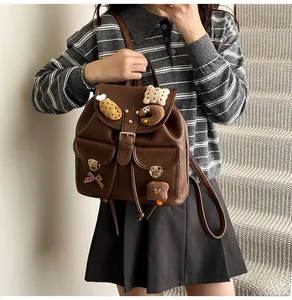 Brown vintage PU leather backpack with cute plush pins and bow ties shown on a model
