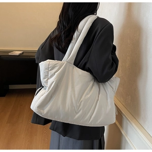 Detail of white quilted nylon puffer tote bag with padded strap and side drawstring