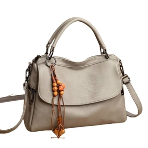 Gray lychee leather handbag with top handle and beaded tassel pendant on white background