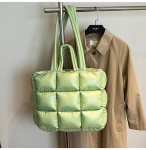 Detail of light green puffer tote bag with quilted square patterns and satin metallic finish