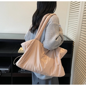 Détail d'un sac cabas beige matelassé montrant la texture rembourrée et la bandoulière