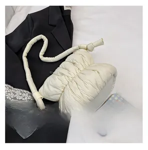 Close-up of creamy white puffy cloud bag featuring pleated texture and knot shoulder strap