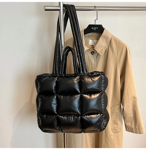 Close-up of black puffer tote bag showing quilted texture and glossy finish details