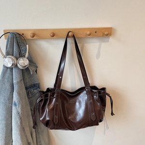 Detail of vintage brown PU leather shoulder bag with drawstring and metal hardware