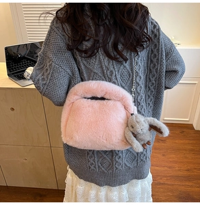 Detail of pink plush shell handbag with chain strap and cute rabbit pendant charm