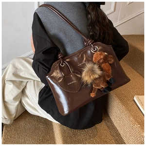 Dettaglio della borsa a spalla in pelle cerata con ciondolo a cuore e cammello di peluche
