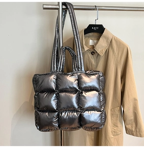 Detail of silver metallic puffer tote bag with quilted padding and dual handles