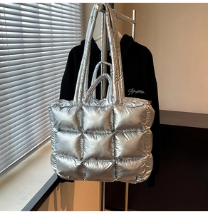 Detail of silver metallic quilted tote bag with wide shoulder straps and puffy texture