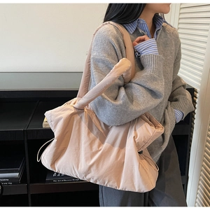 Detail of a large quilted nylon tote bag in light pink with wide shoulder strap