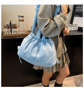 Model wearing a light blue nylon tote bag with drawstring closure and quilted design