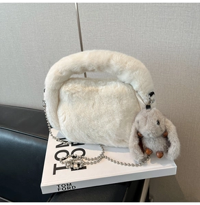 Détail du sac à main en peluche blanche avec pendentif lapin et bandoulière chaîne argent