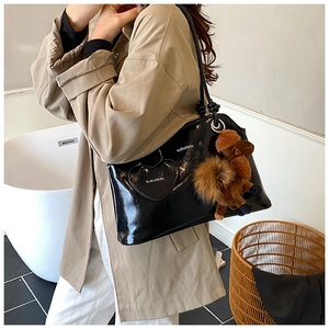 Détail du sac bandoulière en similicuir noir brillant avec poche cœur et breloque caniche