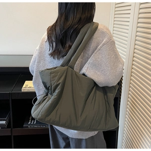 Detail of olive green quilted shoulder bag showing side drawstring and matte nylon texture