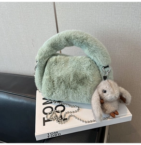 Détail du sac à main en peluche vert menthe avec chaîne argentée et bijou lapin