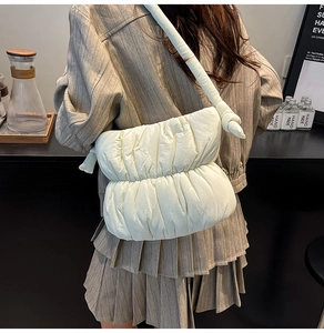 Detail view of cream puffer crossbody bag with knotted strap and quilted texture