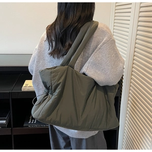 Detailed back view of model carrying a quilted olive green puffer tote bag with drawstrings