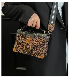 Detail of leopard print suede crossbody bag with gold lion head buckle and rivets