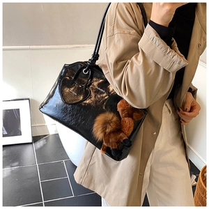 Détail du cabas en cuir ciré noir brillant avec charms peluche chameau et cœur