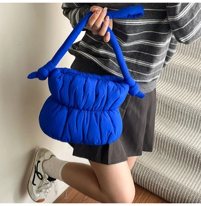 Detail of royal blue quilted cloud bag featuring soft padded texture and unique knot handle