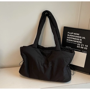 Détail de ce sac fourre-tout en nylon noir matelassé avec cordon latéral et longues anses