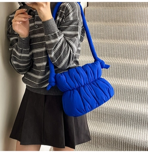 Detail of blue quilted puffer bag with knotted shoulder strap and cloud design