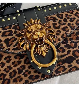 Detail of leopard print faux suede bag featuring gold lion head buckle and metal rivets