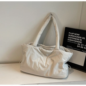 Détail du sac cabas matelassé beige clair avec cordons latéraux et texture douce gonflée