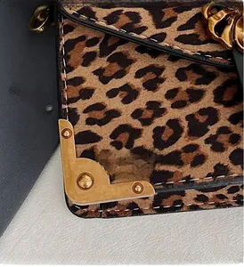 Detail of leopard print suede bag featuring vintage gold metal corner and stud accents