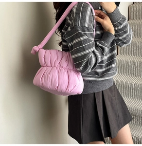 Close-up of pink puffer cloud bag with quilted design and decorative knot shoulder strap
