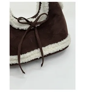 Close-up of brown faux suede shoulder bag with white fleece trim and bow detail