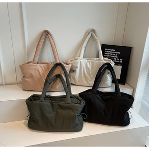 Quilted down fabric tote bags in four neutral colors displayed on white steps