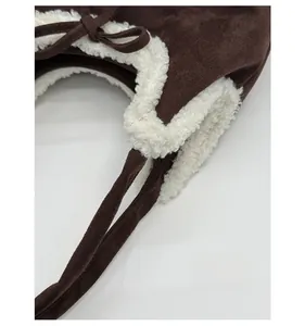 Close-up of brown suede fabric and white faux shearling trim with bow detail