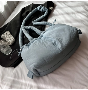Macro shot of light blue quilted nylon bucket bag with a stylish knotted shoulder strap