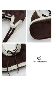 Detail of brown suede bucket bag with white faux shearling trim and decorative bow