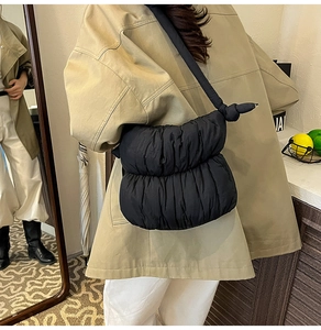 Detail of the black quilted puffer bag texture with decorative shoulder strap knot