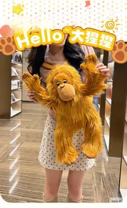 Detailed view of soft long-fur orangutan plush doll held by a model for scale