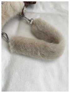 Detailed close-up of beige plush faux fur shoulder strap with silver metal swivel hooks