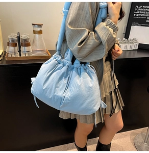 Detail of light blue padded tote bag with drawstring closure and knotted strap handle