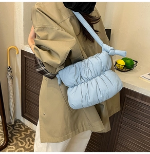 Close-up of light blue quilted puffy bag featuring a stylish knot detail on the strap