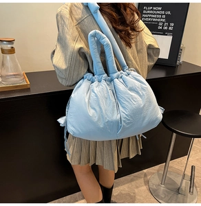 Close-up of quilted light blue bucket bag with drawstring closure and wide shoulder strap