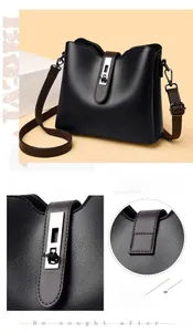 Détail du fermoir argenté sur sac seau noir avec bandoulière marron et texture cuir