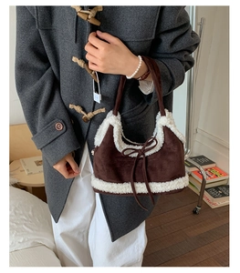 Close-up of brown suede shoulder bag with plush shearling trim and bow detail