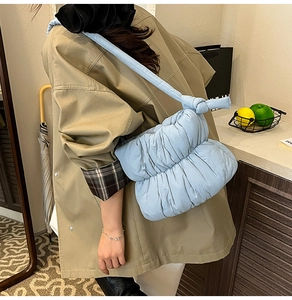 Lifestyle view of a light blue quilted cloud bag with knot strap detail worn by a model