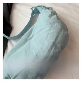 Detail of light blue pleated nylon shoulder bag showing soft texture and puffy design