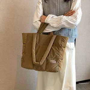 Detail of a large brown quilted tote bag showing puffer texture and dual shoulder straps