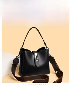 Détail d'un sac seau en cuir noir avec fermoir argenté et bandoulière en tissu marron