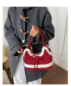 Detail of red suede tote bag with white faux shearling trim and decorative bow