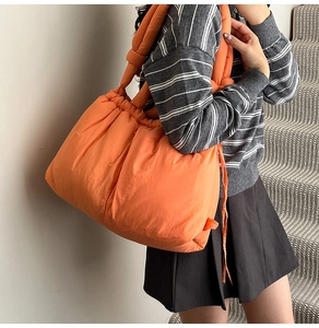 Detail shot of the puffer quilted tote bag with drawstring closure and orange nylon texture