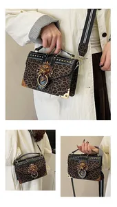 Close-up of leopard print crossbody bag with golden lion head buckle and metal studs